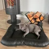 A French bulldog lies on a black dog bed in front of a modern fireplace and a log holder. Produktbild-Vorschau