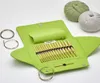 A knitting set with bamboo needles and circular cords laid out in a green case, with two balls of yarn in the background. Produktbild-Vorschau
