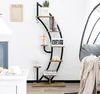 A multi-tiered shelf unit with decorative items and books, placed next to a hanging chair. Náhľad obrázku produktu