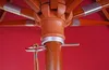A close-up view of the central mechanism of a wooden umbrella, showing the pole, ribs, and a rope mechanism for opening and closing. The umbrella fabric is a solid red. Produktbild-Vorschau