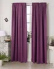 A pair of purple curtains hanging in front of a window, with a chest of drawers and a lamp to the left and a small table to the right. Produktbild-Vorschau