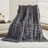 A dark gray plush blanket draped over a chair in a room. Náhled obrázku produktu