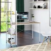 A modern desk with a computer and shelving unit in a well-lit room with a large window. Produktbild-Vorschau