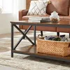 A close-up view of a coffee table in a living room setting, with a couch and rug visible. Produktbild-Vorschau