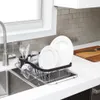 A dish drying rack filled with dishes and glasses next to a kitchen sink. Produktbild-Vorschau