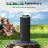 A portable speaker is placed on a rock in an outdoor setting with people in the background. Náhľad obrázku produktu