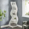 A white wavy corner shelf unit with decorative items and books. Podgląd zdjęcia produktu