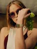 A woman wearing sunglasses and a watch holds a bunch of green grapes. Voir les images du produit