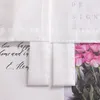 A close-up view of a white sheer curtain with pleats, revealing a floral print of pink roses and some handwritten text behind it. Produktbild-Vorschau