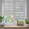 A window with two roller blinds, a plant, a decorative sheep, and a vintage radio on a windowsill. Produktbild-Vorschau