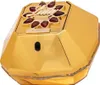 A close-up, angled view of a gold-colored perfume bottle with red gem accents. Voir les images du produit