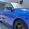 A blue car with a silver sunshade on the windshield parked on a paved driveway next to a building. Podgląd zdjęcia produktu