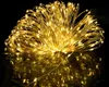 A close-up of a bundle of warm white LED string lights on a reflective black surface. Produktbild-Vorschau