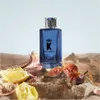 A blue perfume bottle is displayed on a rocky surface with fruits and dried leaves. Náhľad obrázku produktu