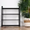A black four-tier shoe rack is shown in a room with a white wall and wooden floor. A large potted plant and a woven basket are to the right of the shoe rack. Anteprima dell’immagine prodotto