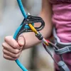 Sicherungsgerät Rama von singing rock; in Gebrauch mit blauer Kletterseil; Hand hält das Gerät. Produktbild-Vorschau