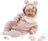 A baby doll dressed in a pink outfit, lying on a white background. Podgląd zdjęcia produktu