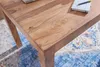 A close-up view of a wooden table with a rug underneath. Anteprima dell’immagine prodotto