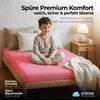 A young boy sitting cross-legged on a pink bedsheet in a bedroom setting. Náhľad obrázku produktu