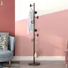 A coat rack with a shirt and a handbag is placed in a room with pink and white walls and a blue armchair. Produktbild-Vorschau