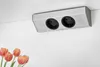A silver electrical outlet strip with two sockets is mounted on a white ceiling, with a few tulips in the foreground. Voir les images du produit