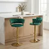 Two emerald green velvet bar stools with gold bases are shown in a modern kitchen setting. Voir les images du produit