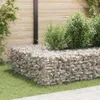 A gabion planter box filled with rocks and plants, set in a garden with a wooden fence in the background. Podgląd zdjęcia produktu
