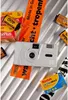 A white Kodak camera is surrounded by Kodak film rolls and packaging on a striped surface. Anteprima dell’immagine prodotto