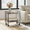 A serving cart with flowers and books next to a sofa. Voir les images du produit
