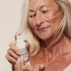 A woman is holding a bottle of serum. Produktbild-Vorschau
