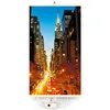 A vertical infrared heating panel with a printed image of the Manhattan skyline at night, hanging from a hook. Produktbild-Vorschau