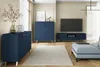 A modern living room with navy blue furniture, a TV, and a light-colored rug. Podgląd zdjęcia produktu