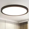 A modern, round LED ceiling light with a black frame is mounted on a white ceiling. Produktbild-Vorschau