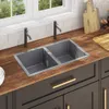 A modern kitchen sink area with a double basin sink, faucets, wooden countertop, and cabinets. Voir les images du produit