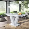 A modern dining room with a white high-gloss extendable dining table and chairs, set against a backdrop of large windows overlooking a garden. Produktbild-Vorschau