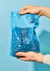 Hands holding a bag of blue candies. Produktbild-Vorschau