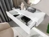 A white console table with an open drawer, displaying various items inside. Náhled obrázku produktu