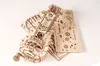 A wooden 3D puzzle of a hurdy-gurdy is shown on a white background, with unassembled puzzle pieces fanned out behind it. Produktbild-Vorschau