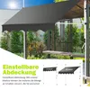 An outdoor awning is shown extended over a wooden bench and pergola structure, with lush greenery in the background. The sun is shining brightly in the upper left corner. Produktbild-Vorschau