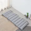 A gray floor cushion is laid out on a patterned rug in a room with white walls and sheer curtains. Produktbild-Vorschau
