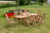 A wooden garden furniture set is arranged on a lawn with flowers in the background. Náhled obrázku produktu