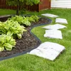 A garden scene showing a flexible plastic edging separating a mulched flower bed from a lawn, with stepping stones visible on the grass. Produktbild-Vorschau