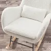 A close-up view of a white, fluffy rocking chair with wooden legs and a black metal frame, placed on a wooden floor. Produktbild-Vorschau