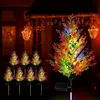 Outdoor decorative solar lights shaped like cypress trees, illuminated with colorful LEDs, placed in a garden setting at night. Anteprima dell’immagine prodotto