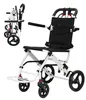 A white and black foldable transport wheelchair is shown against a white background. A smaller, folded version of the wheelchair is visible in the upper left corner. Náhľad obrázku produktu