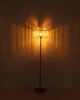 A floor lamp with a ribbed shade casts light and shadows on a wall. Náhľad obrázku produktu