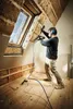 A person is using a nail gun to insulate an attic space near a skylight. Produktbild-Vorschau