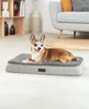 A small dog lies on a gray dog bed in a living room setting. Náhled obrázku produktu