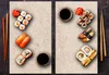 A top-down view of two beige serving boards filled with various sushi dishes and accompaniments. Náhled obrázku produktu