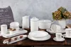 A collection of white ceramic tableware with gray trim, arranged on a wooden surface. Anteprima dell’immagine prodotto
